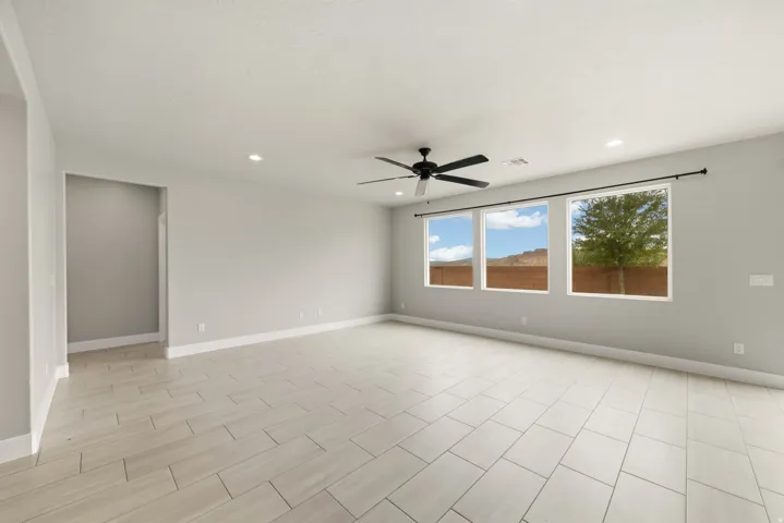 Spacious room featuring large format tile flooring, a contemporary ceiling fan, recessed lighting, and a wall of three windows