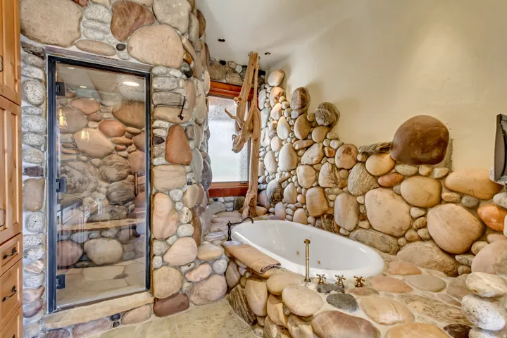 Bathroom featuring extensive river rock wall cladding and flooring