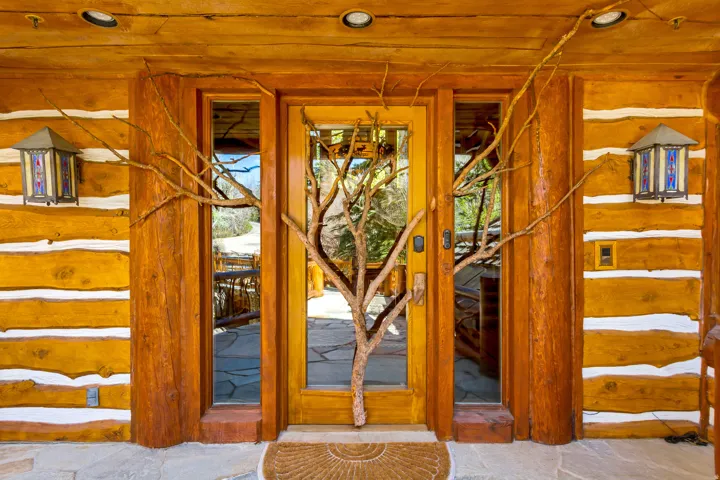 Log cabin exterior with a natural wood front door featuring a branch-like decorative element