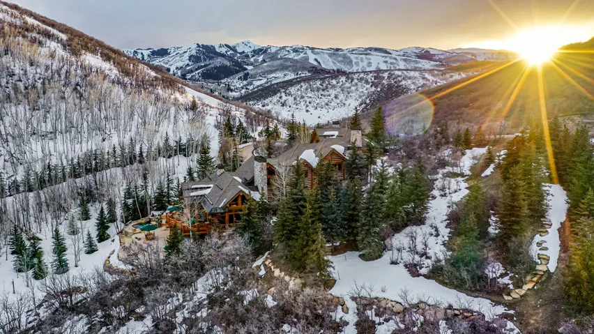Expansive mountain property featuring a multi-level structure with stone and wood siding, multiple outdoor decks, and two built-in circular hot tubs