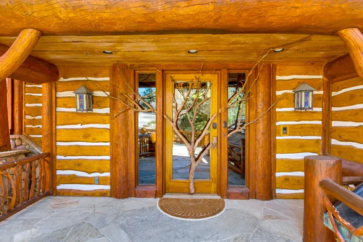 Log cabin entry featuring a natural wood door with glass paneling, flanked by glass sidelights