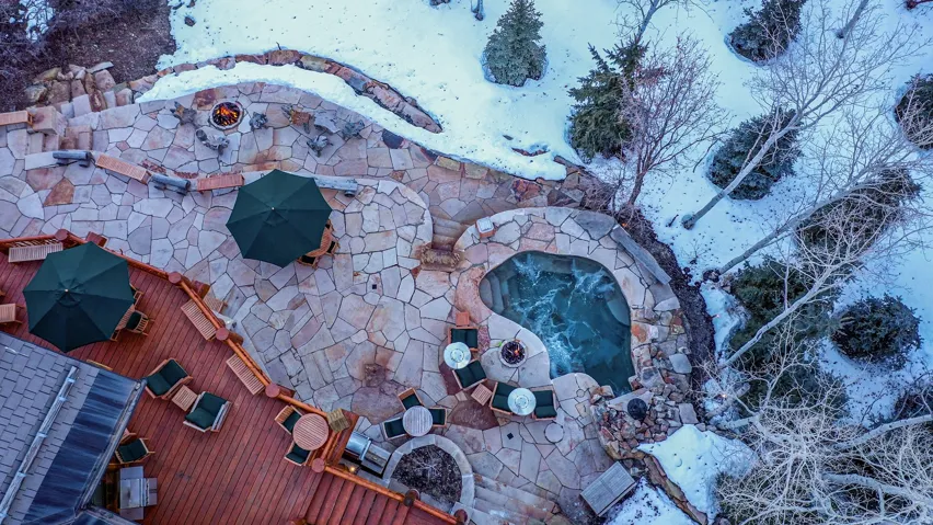 Expansive outdoor entertainment area featuring a flagstone patio, built-in spa, fire pit, and wood deck