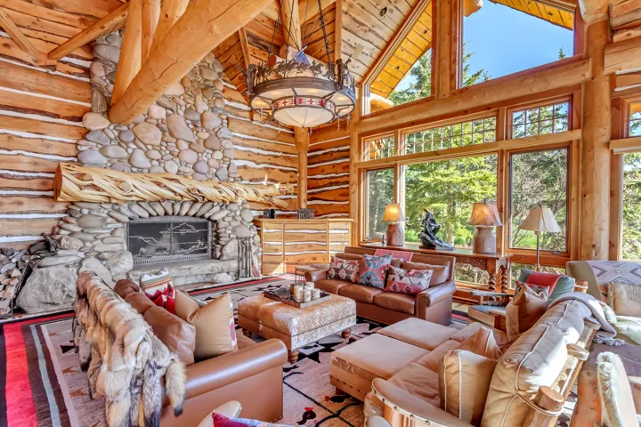Grand living room featuring a floor-to-ceiling stone fireplace with a substantial log mantel