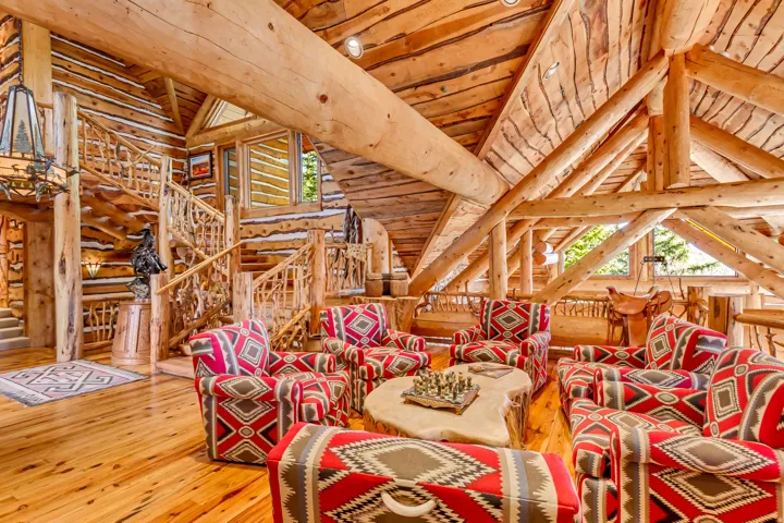 Expansive living area with exposed timber log construction, vaulted wood-plank ceilings, and wide-plank wood flooring