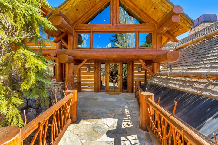 Log cabin exterior featuring a prominent gabled entry with extensive glazing