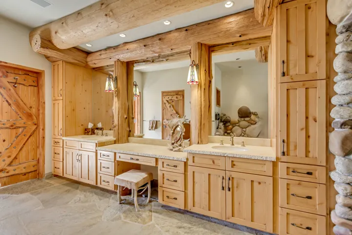 Rustic bathroom vanity area featuring natural wood cabinetry and exposed log beams