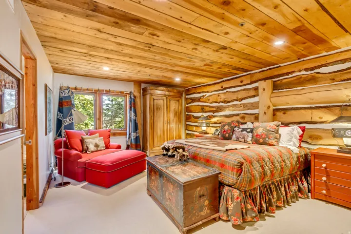Room featuring a log wall, wood-paneled ceiling, and recessed lighting