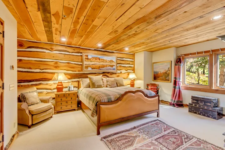 Spacious room featuring log wall accents, wood-paneled ceiling with recessed lighting, and multiple windows with wood trim