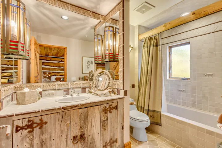 Bathroom featuring a rustic wood-finish vanity with ornate hardware, an undermount sink, and a large mirror