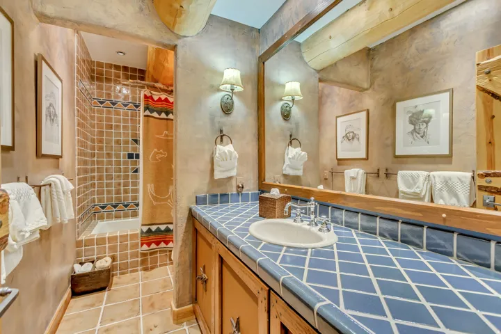 Bathroom featuring a blue diamond-patterned tiled countertop, a built-in sink, and a chrome faucet