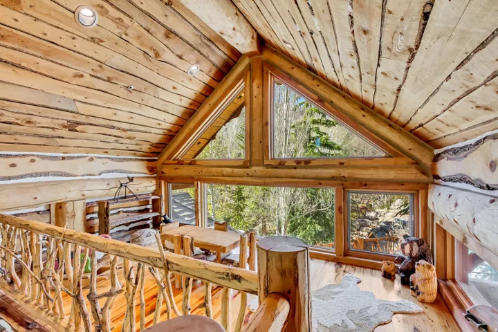 Expansive wood-paneled interior featuring a log railing system and a triangular window frame