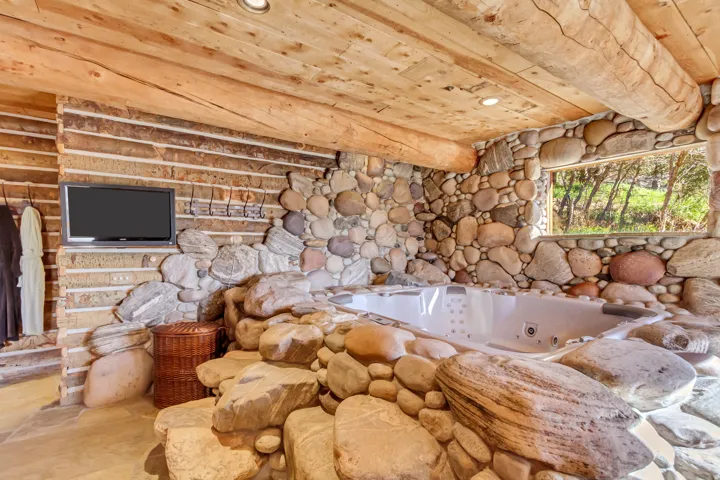 Built-in hot tub surrounded by natural stone and a log-style wall