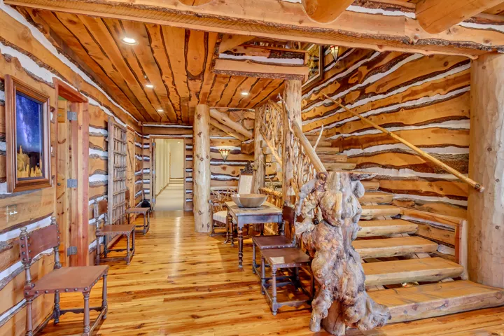 Rustic interior featuring log walls, wood-finish flooring, a built-in staircase with a log railing, wood plank ceiling, and recessed lighting