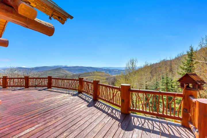 Expansive wood deck featuring rustic branch railings and a robust log beam overhead