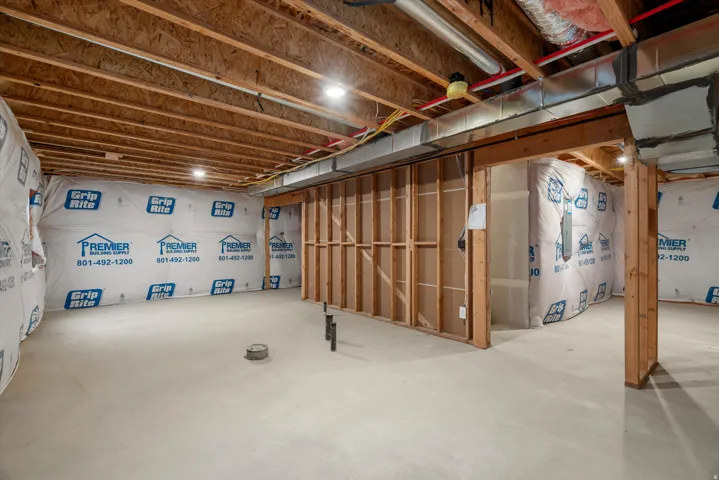 Unfinished basement space featuring exposed wood joists and concrete flooring