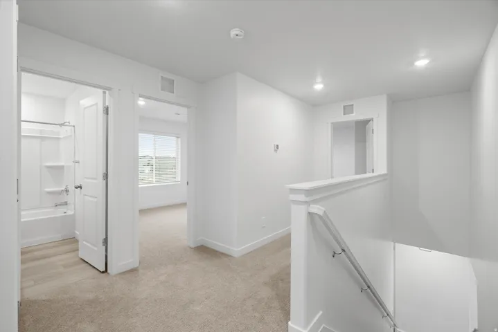 Carpeted landing featuring a half-wall railing, recessed lighting, and white trim
