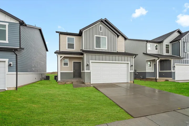 Contemporary two-story residence featuring a combination of vertical and horizontal siding, an attached two-car garage, concrete driveway, and a front lawn