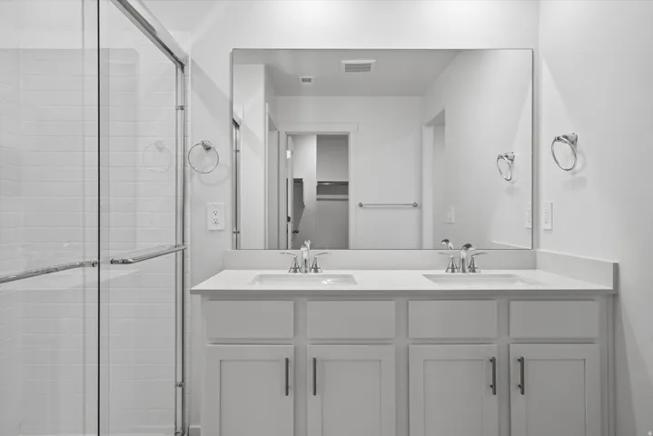 Bathroom featuring a dual vanity with white cabinetry, light-toned countertops, and chrome fixtures