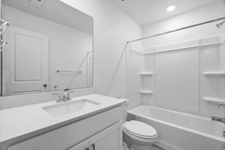 Modern bathroom featuring a white vanity with an integrated sink, a speckled light-colored countertop, and a chrome faucet