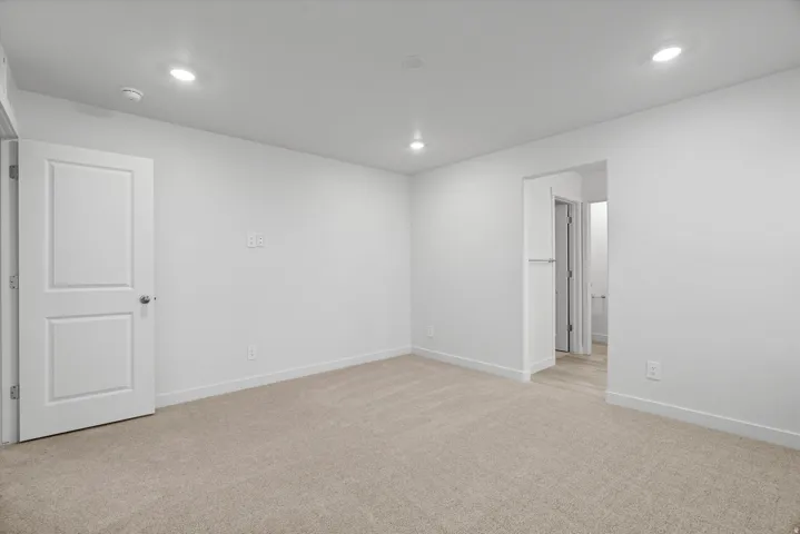 Neutral-toned carpeting, white walls, recessed ceiling lighting, and crisp white trim