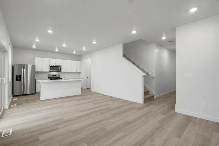 Contemporary kitchen featuring white cabinetry, stainless steel appliances, a center island, and wood-finish flooring
