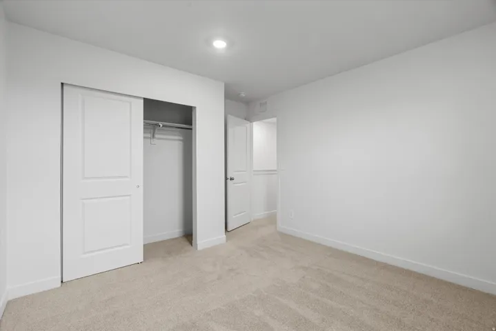 Carpeted room featuring a double-door closet with a hanging rod