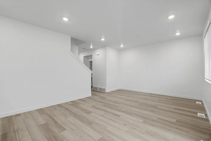 Spacious interior featuring wood-finish flooring, recessed lighting, white baseboards, and a window with horizontal blinds