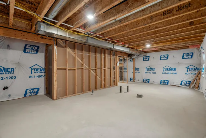 Unfinished basement featuring a concrete floor, exposed wood joists, framed interior walls, and visible plumbing rough-ins