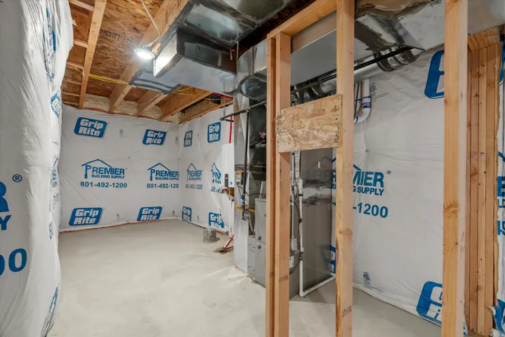 Unfinished basement with exposed ceiling joists, concrete flooring, and insulated walls