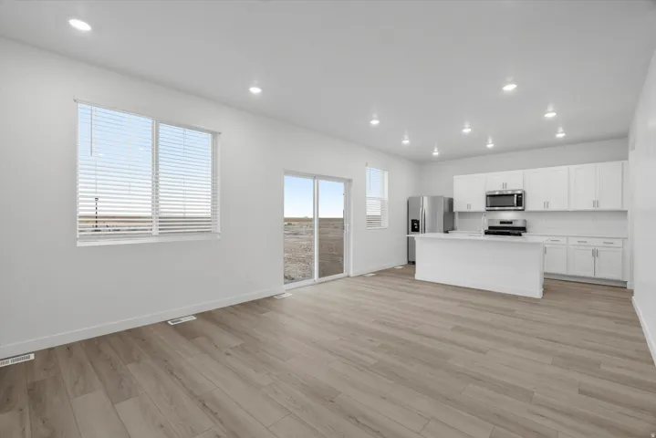 Open-concept living area with wood-finish flooring, recessed lighting, and a modern kitchen
