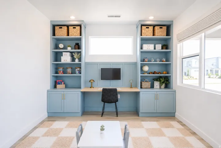 Built-in custom cabinetry with shelving, integrated desk, recessed lighting, and large windows with roller shades