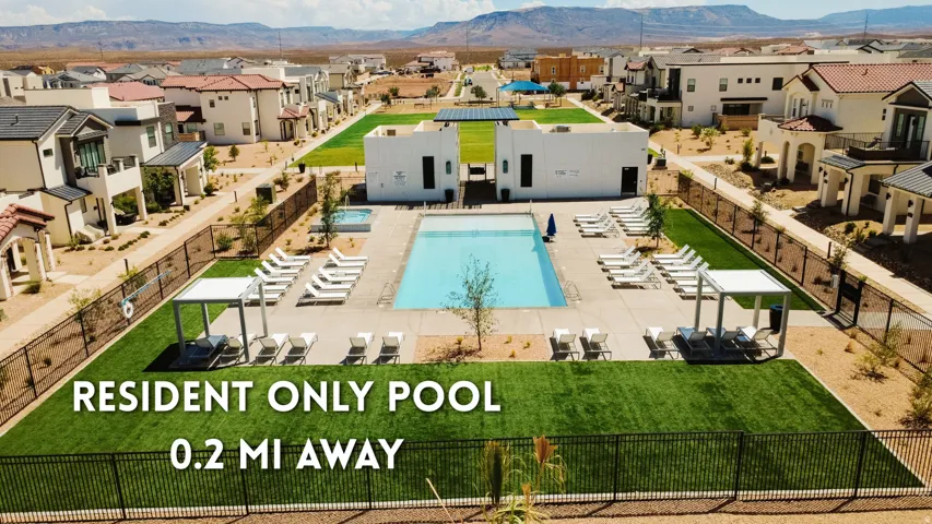Community swimming pool with an adjacent spa, surrounded by artificial turf and desert landscaping