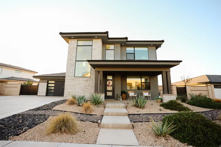 Modern exterior with stone and stucco finishes, a covered entry, and a contemporary garage door