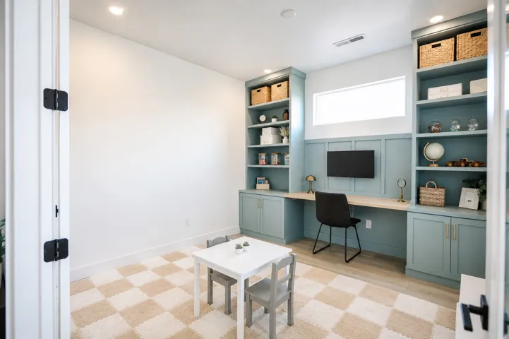 Dedicated home office featuring custom built-in cabinetry with shelving and lower storage, wood-finish desk surface, recessed lighting, and a geometric patterned wood-finish floor