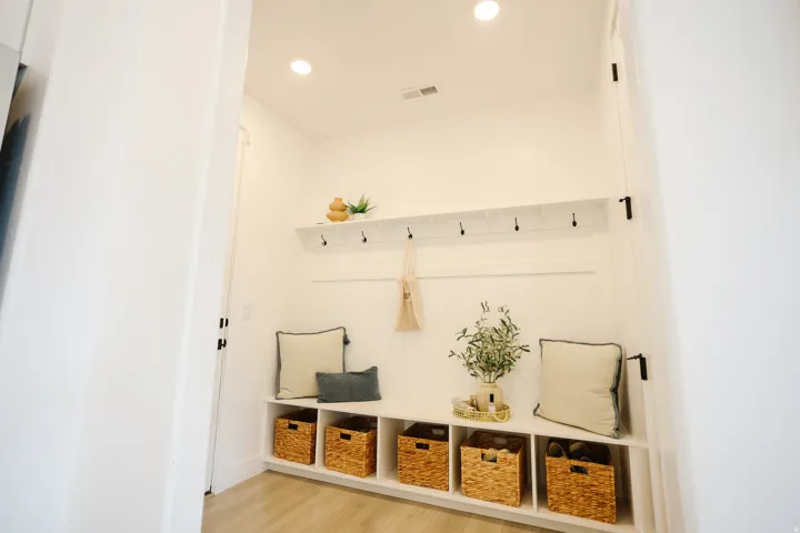 Built-in entryway bench with integrated storage cubbies, wall-mounted coat rack, and recessed lighting