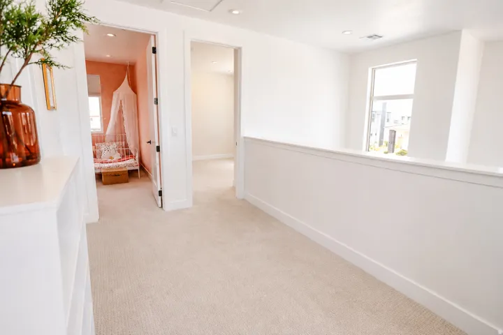 Open hallway with neutral carpeting, white walls, recessed lighting, and modern window
