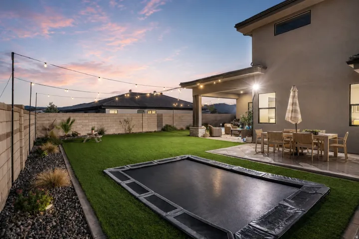 Expansive backyard featuring a manicured lawn, a large paved patio, and a covered outdoor living area