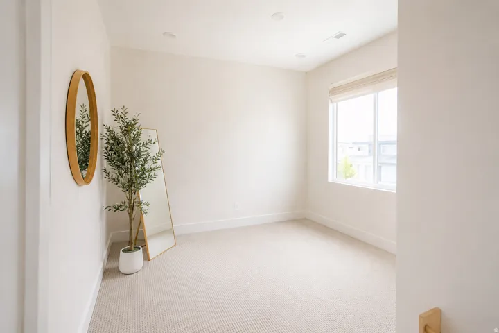 Bright, light-filled room with neutral wall finishes, recessed ceiling lighting, and large window framing natural daylight