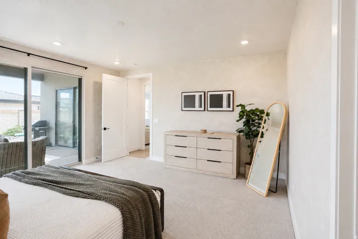 Recessed lighting illuminates a spacious room featuring light-toned carpeting and neutral wall finishes