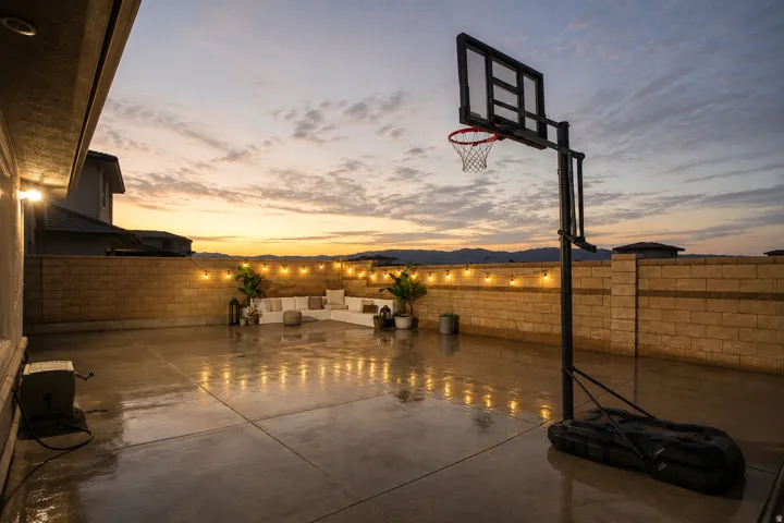 Expansive concrete patio with block wall perimeter, integrated wall lighting, and mountain backdrop