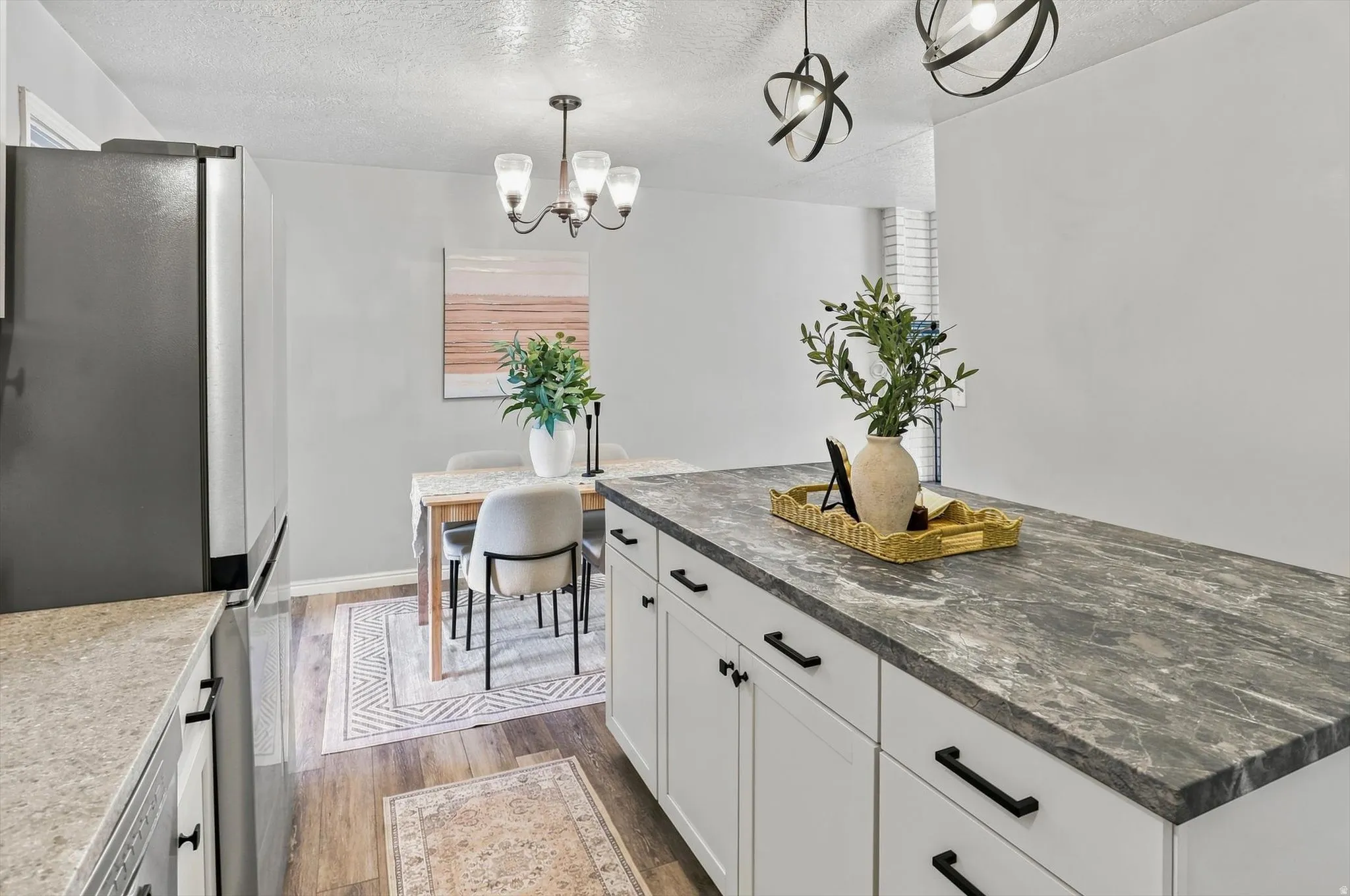 Spacious kitchen island with a dark, veined countertop, white cabinetry, and matte black hardware