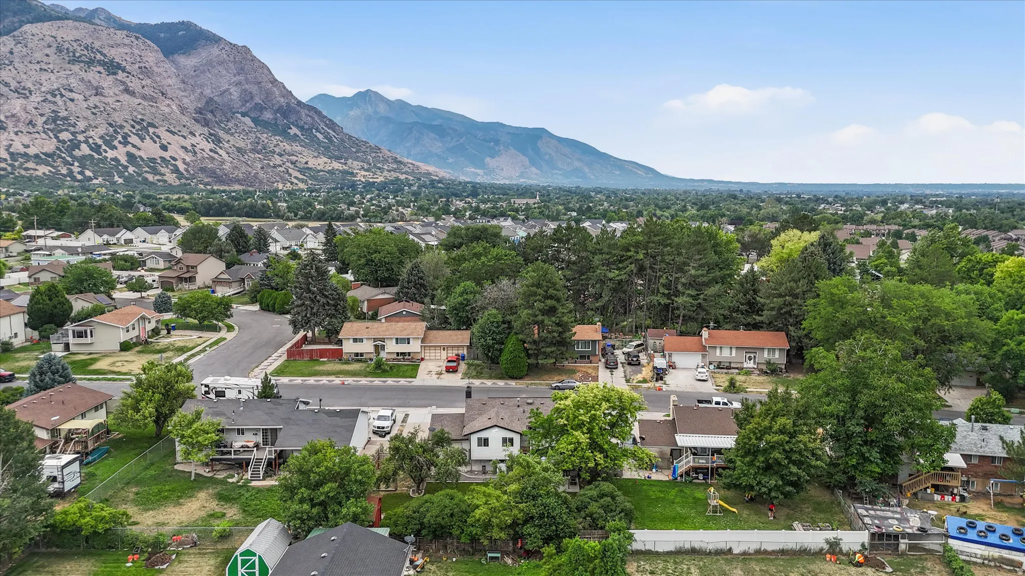 Residential neighborhood with varied architectural styles and mature trees, set against a backdrop of distant mountains