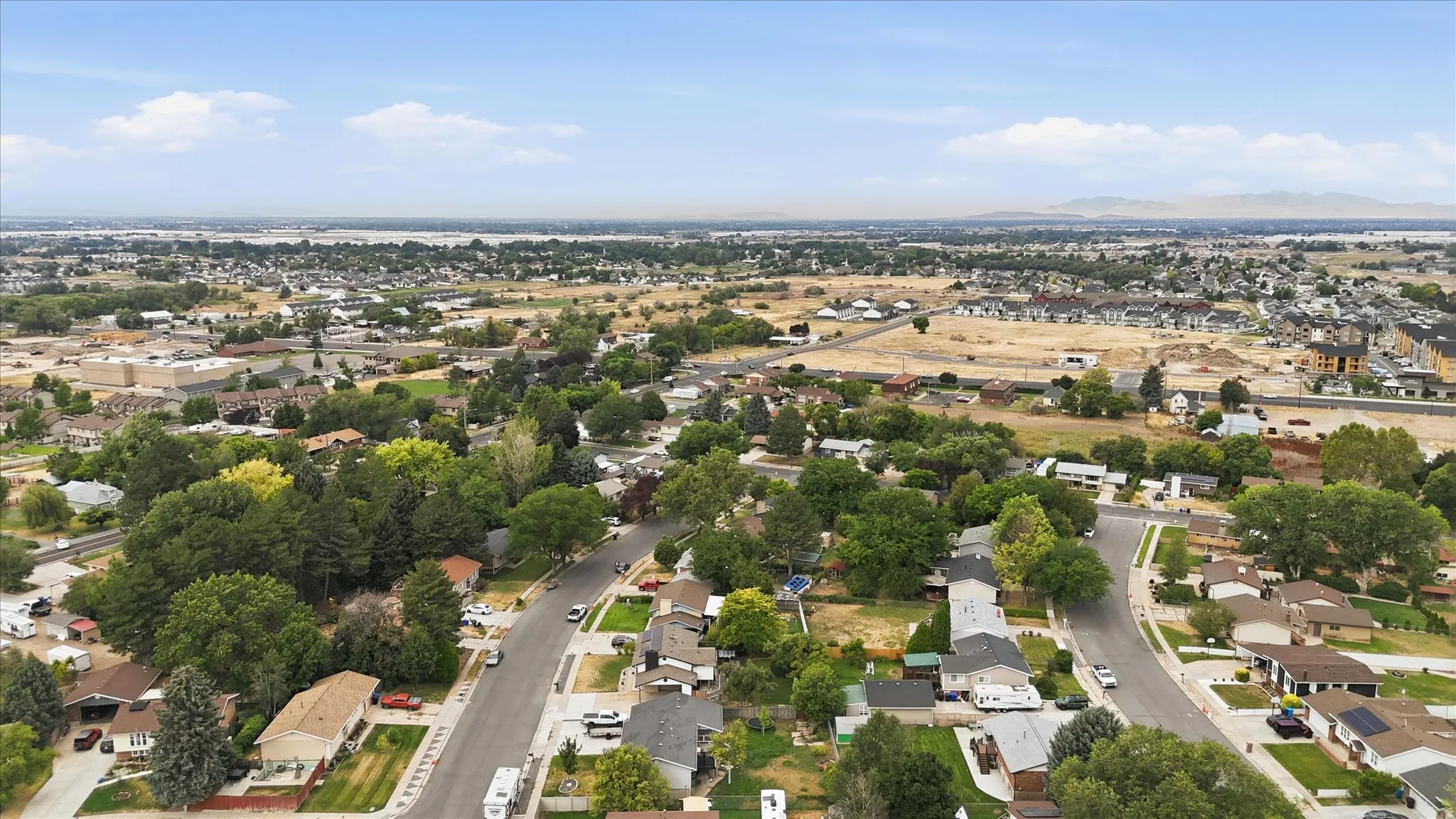 Residential neighborhood featuring a mix of mature trees and open land, with distant mountains providing a scenic backdrop