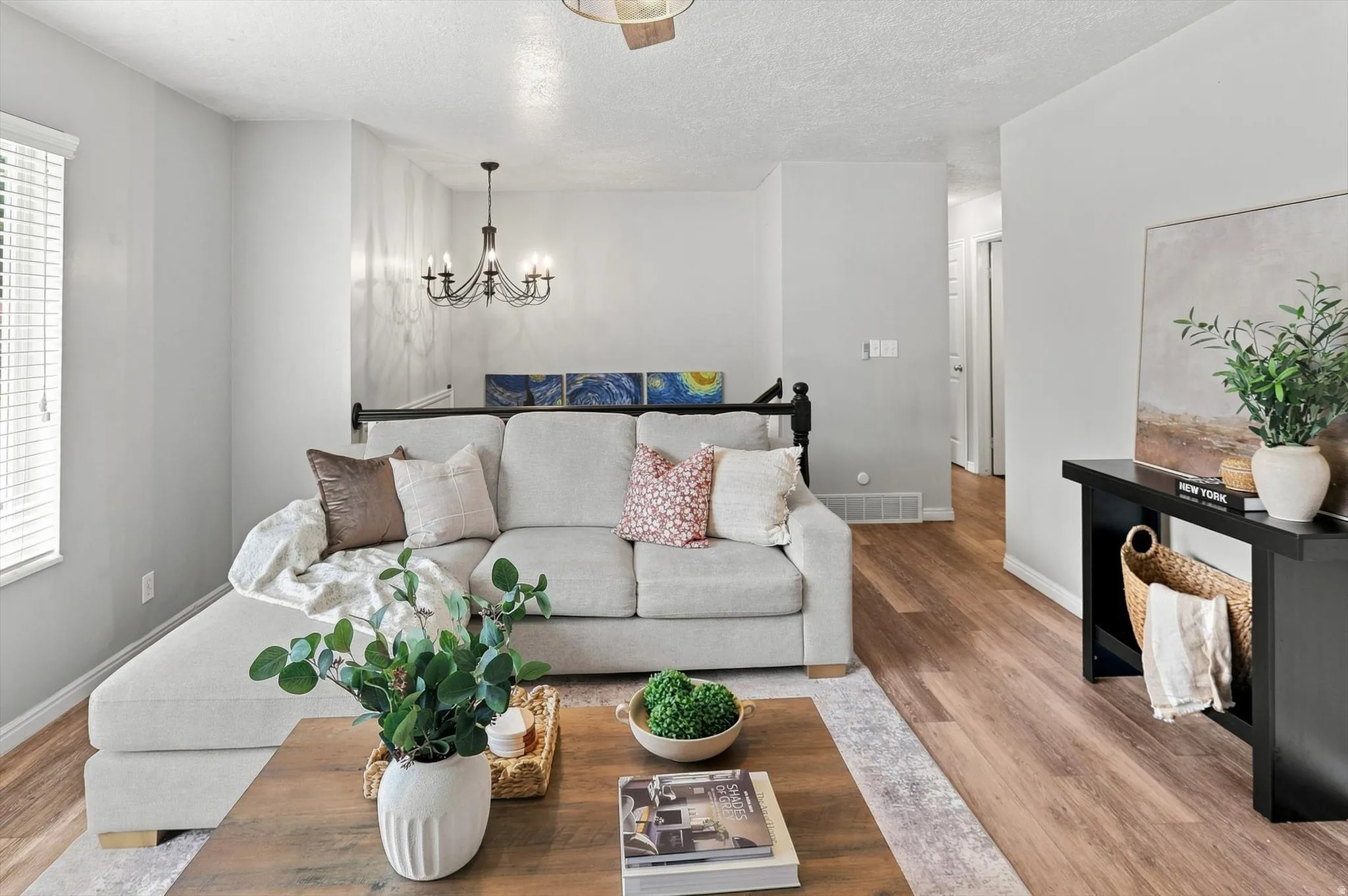Living area featuring wood-finish flooring, light-toned walls, and a window with blinds