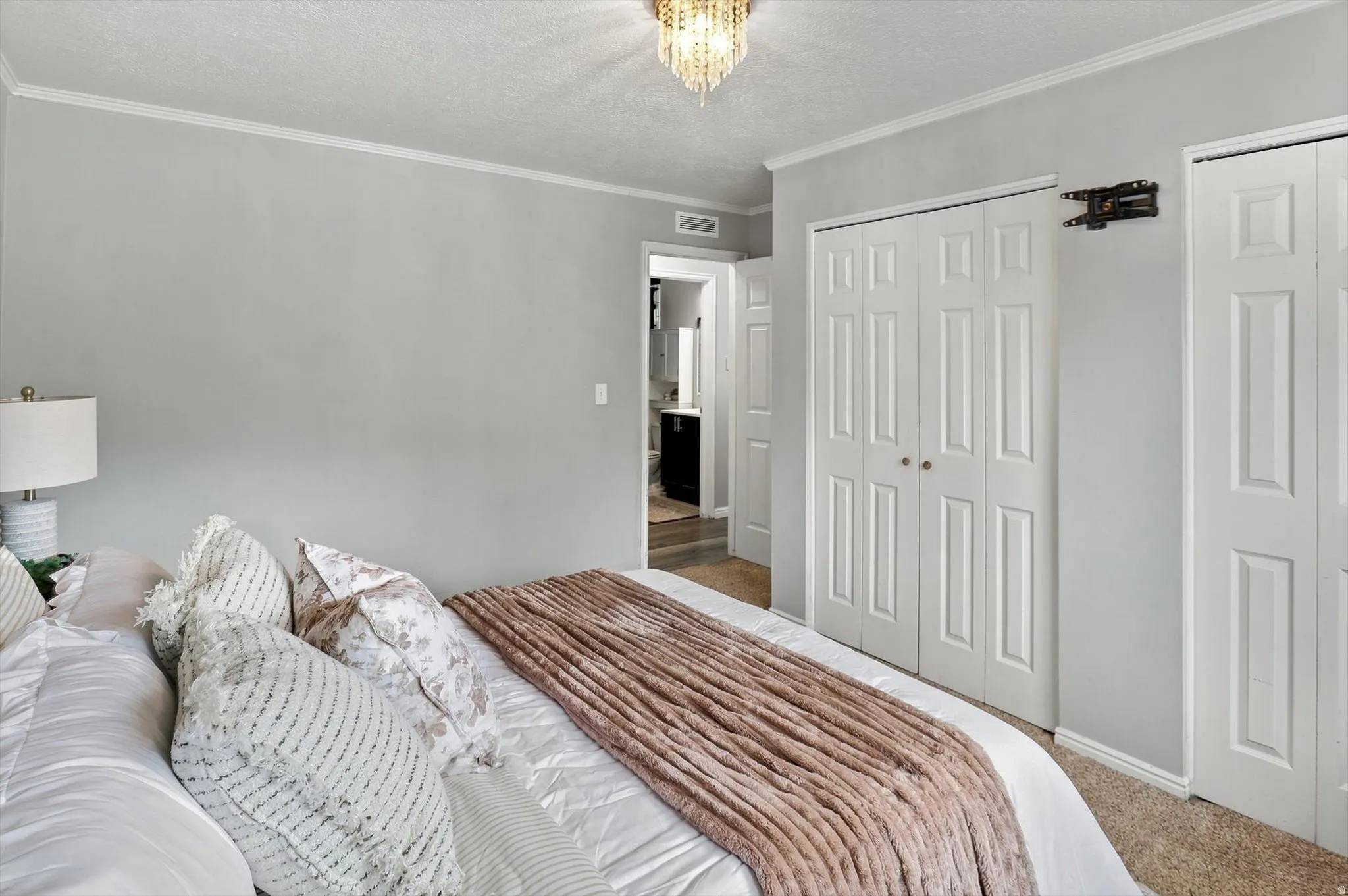 Bedroom featuring light gray walls, white crown molding, and textured carpeting