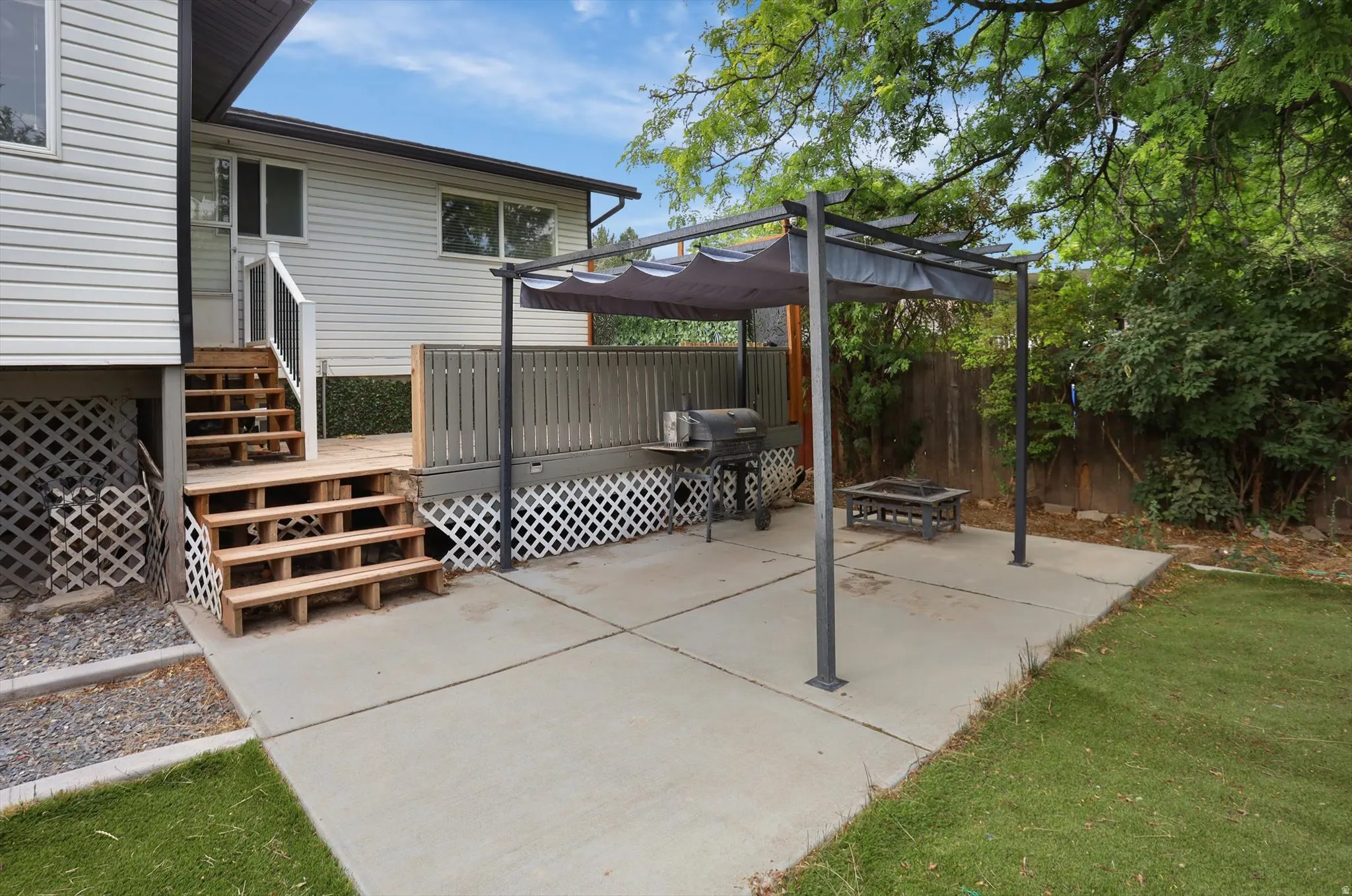 Expansive concrete patio featuring a pergola, offering sheltered outdoor space