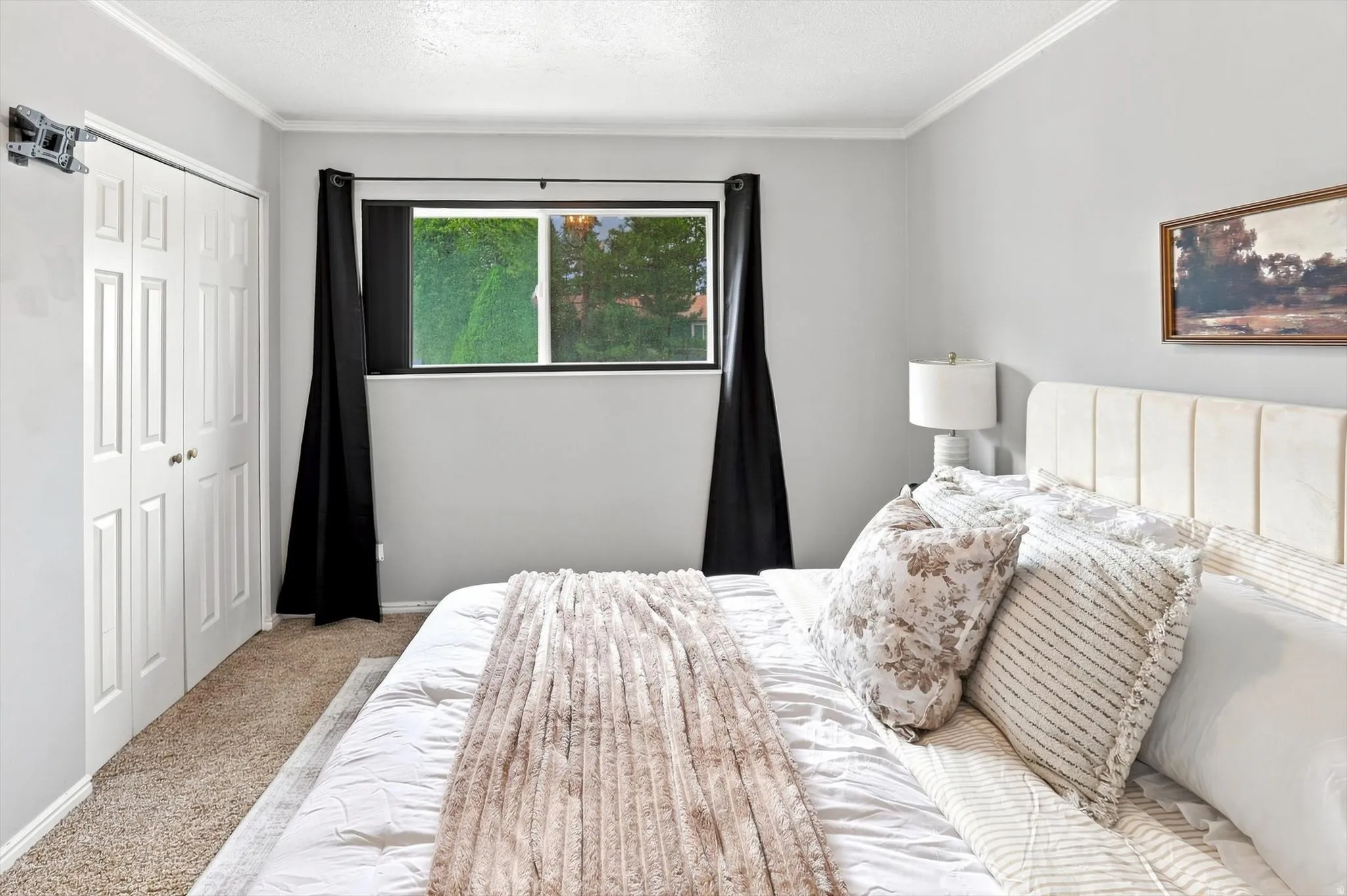 Neutral-toned room featuring a window with black privacy drapes, a multi-pane bi-fold closet, and crown molding