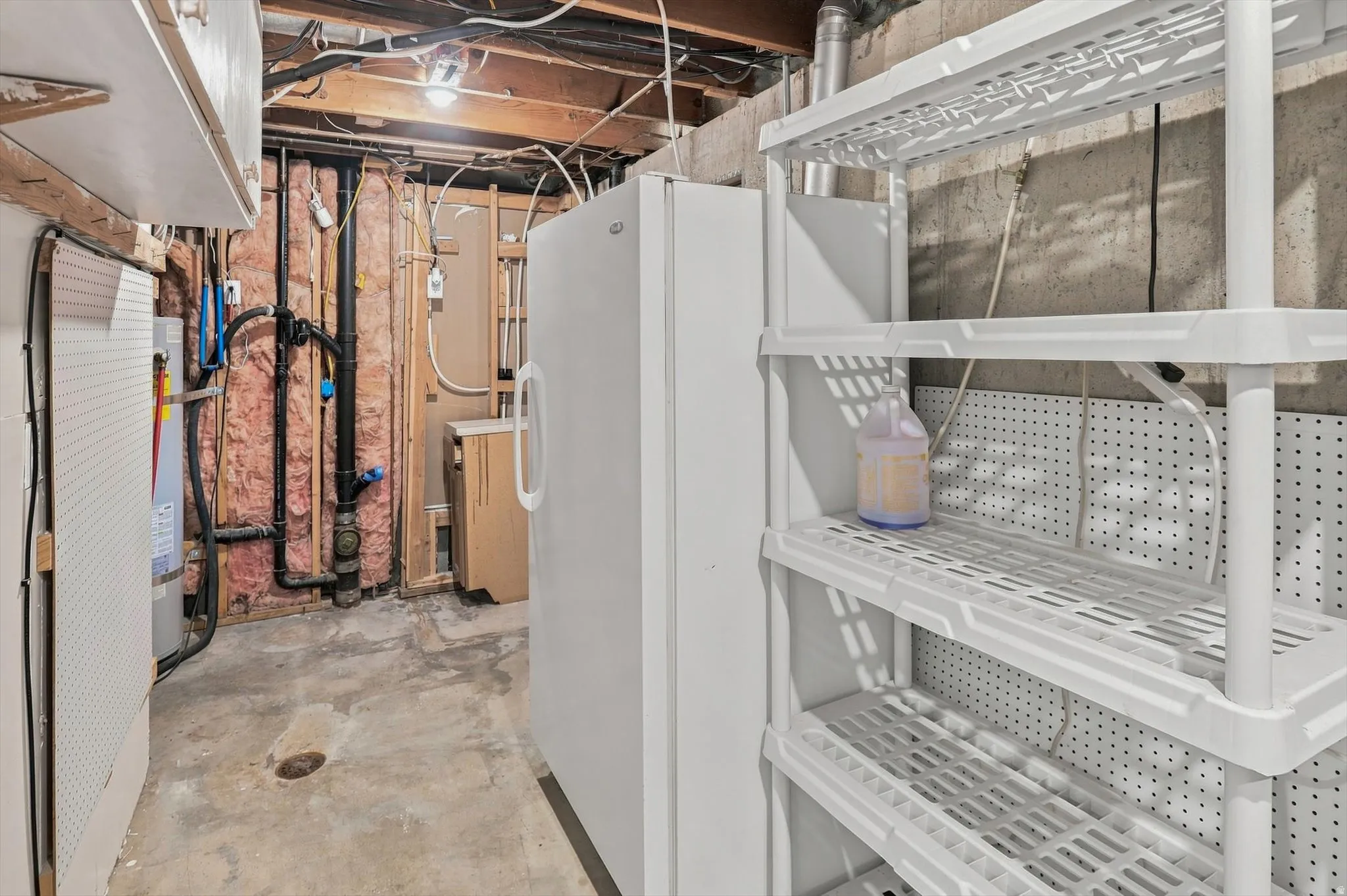 Unfinished basement utility area featuring exposed joists, concrete flooring, and visible plumbing