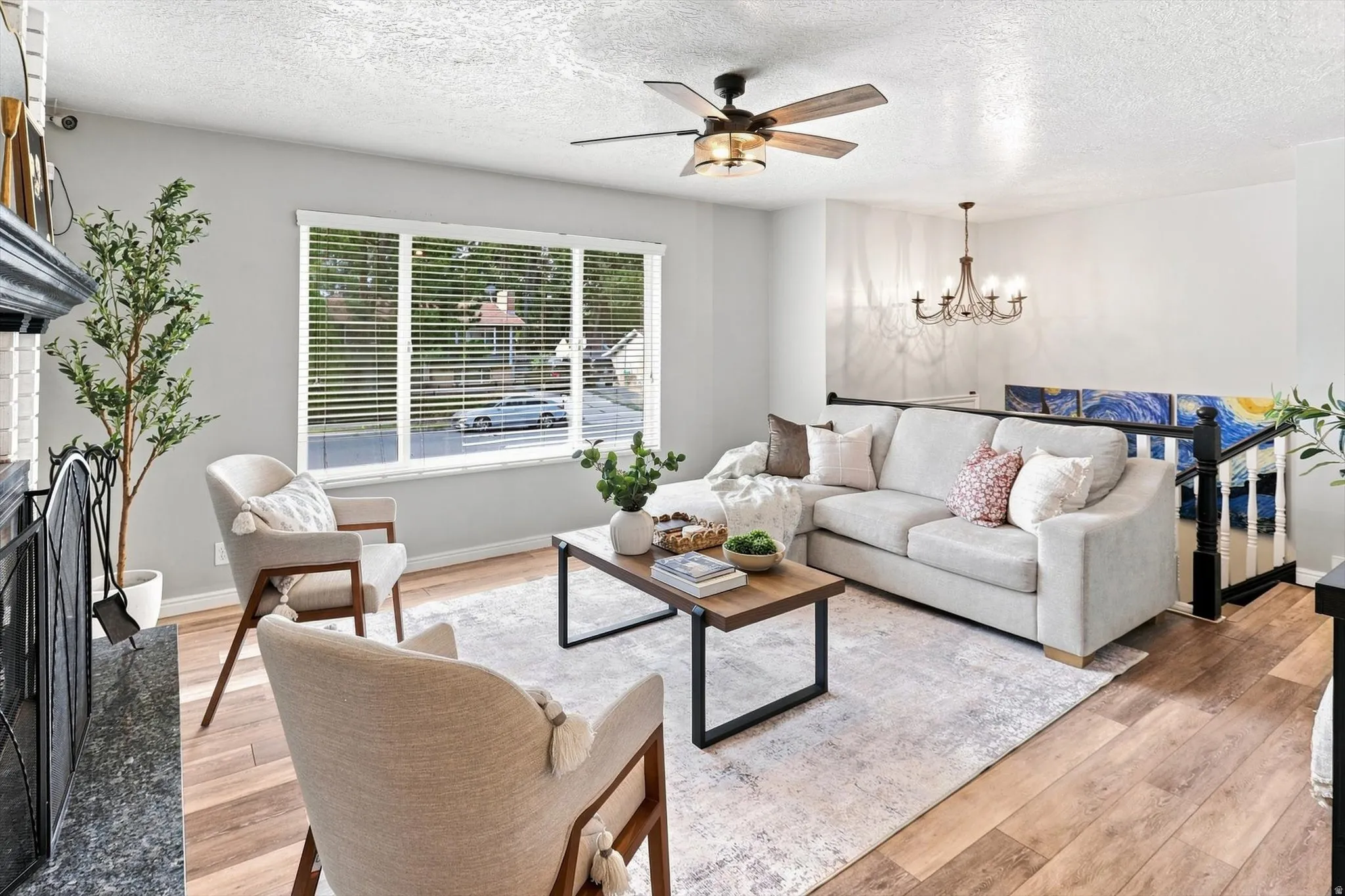 Bright living area featuring wood-finish flooring, a contemporary ceiling fan, and a chandelier