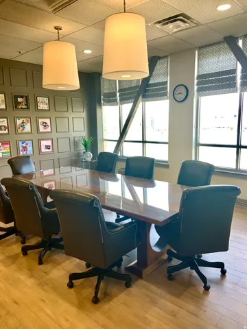 Conference room featuring wood-finish flooring, a large wood table with a glass top, and two suspended drum pendant lights
